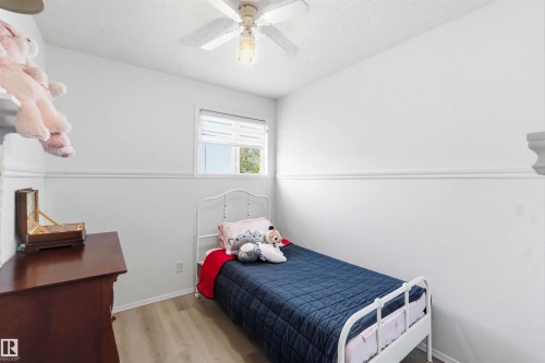 Bright interior room featuring a window with integrated blinds, a ceiling fan with lighting, wood-finish flooring, and white wall paneling - 18808 72A Avenue, Edmonton, AB 