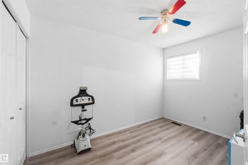 Room featuring wood-finish flooring, a ceiling fan, and a window with horizontal blinds - 18808 72A Avenue, Edmonton, AB 