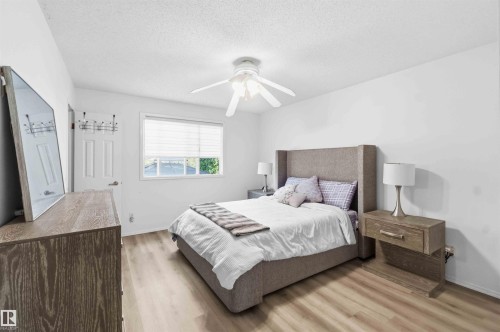 Room featuring wood-finish flooring, a white ceiling fan with light fixture, and a window with horizontal blinds - 18808 72A Avenue, Edmonton, AB 