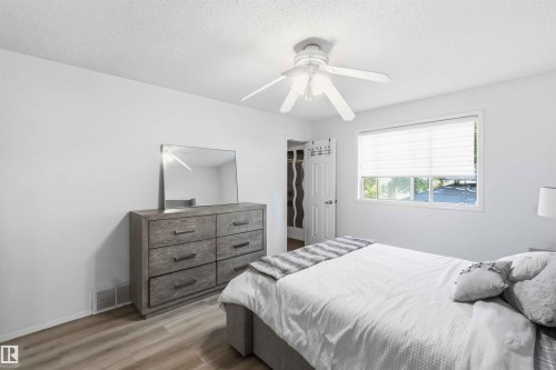Bedroom featuring light wood-finish flooring, white walls, and a ceiling fan with integrated lighting - 18808 72A Avenue, Edmonton, AB 