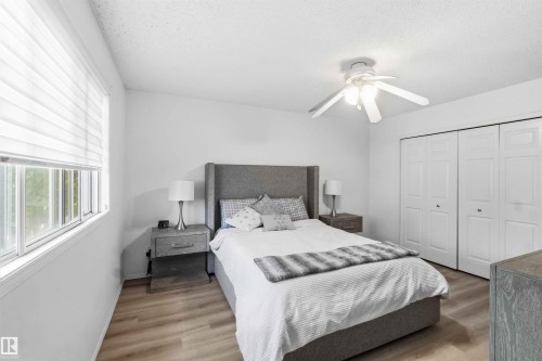 Bedroom featuring wood-finish flooring, a ceiling fan, and white bi-fold closet doors - 18808 72A Avenue, Edmonton, AB 