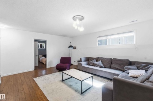 Spacious interior featuring wood-finish flooring, white walls, and a contemporary ceiling light fixture - 18808 72A Avenue, Edmonton, AB 