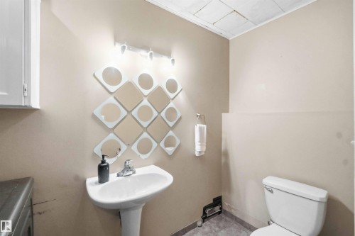 Pedestal sink with chrome faucet, wall-mounted vanity lighting, and mosaic-style wall decor - 18808 72A Avenue, Edmonton, AB 