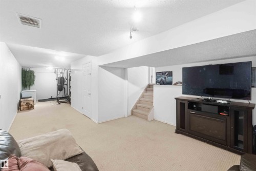 Spacious lower level featuring light-toned carpeting, white walls, recessed lighting, and a partial staircase - 18808 72A Avenue, Edmonton, AB 