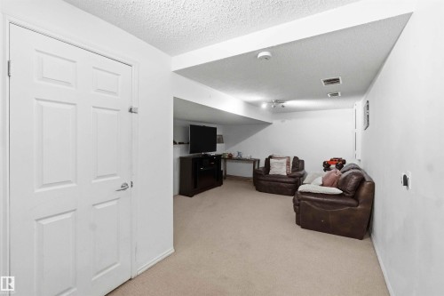 Expansive recreation room featuring neutral carpeting, white painted walls, recessed lighting, and a paneled white door - 18808 72A Avenue, Edmonton, AB 