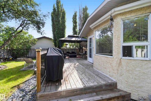 Wood-finish deck with black metal railings, leading to a covered gazebo area - 18808 72A Avenue, Edmonton, AB 