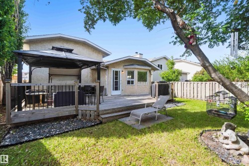 Expansive backyard featuring a spacious wood deck, integrated gazebo, manicured lawn, and mature trees - 18808 72A Avenue, Edmonton, AB 