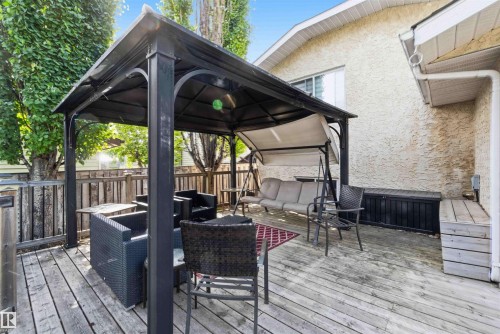 Wood-finish deck featuring a black metal gazebo with a fabric canopy, a privacy fence, and a neutral stucco exterior - 18808 72A Avenue, Edmonton, AB 