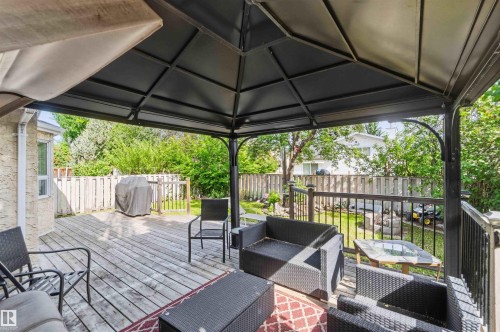 Spacious outdoor deck area featuring a dark metal gazebo with a solid roof, wood plank flooring, and dark railing - 18808 72A Avenue, Edmonton, AB 