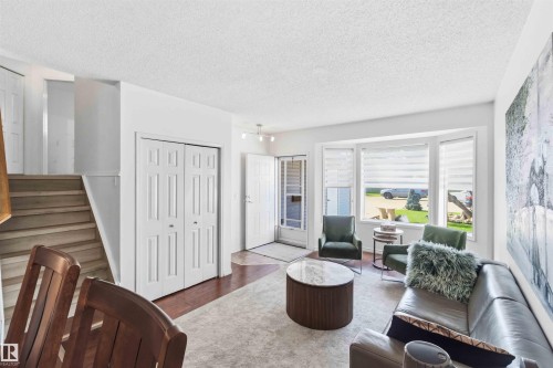 Living area featuring a bay window, wood-finish flooring, and a patterned area rug - 18808 72A Avenue, Edmonton, AB 