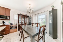 Spacious dining area featuring white tile flooring, a multi-light chandelier, and a sliding glass patio door - 