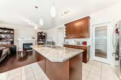 Open-concept kitchen featuring an island with an undermount sink, granite countertop, and pendant lighting - 