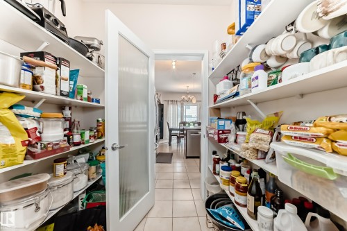 Spacious pantry featuring extensive open shelving, a frosted glass panel door, and tile flooring - 8730 180A Avenue, Edmonton, AB 