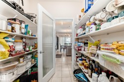 Spacious pantry featuring extensive open shelving, a frosted glass panel door, and tile flooring - 