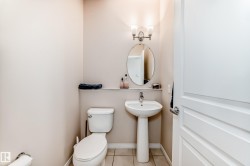 Pedestal sink with a wall-mounted oval mirror, illuminated by a brushed nickel vanity light fixture - 