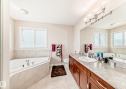 Bathroom featuring a corner soaking tub, dual windows, large vanity with double sinks, and extensive counter space - 