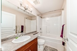 Full bathroom featuring a single vanity with wood-finish cabinetry, a large mirror, and a combination tub and shower - 