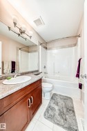 Full bathroom with a wood-finish vanity, integrated sink, and stone-look countertop - 