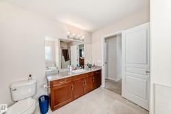 Dual sink vanity with wood-finish cabinetry, light-toned countertop, and undermount sinks - 
