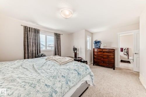 Carpeted room with a ceiling-mounted light fixture, dual windows, and an open doorway revealing a tiled bathroom - 8730 180A Avenue, Edmonton, AB 