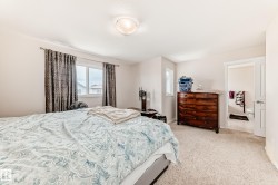 Carpeted room with a ceiling-mounted light fixture, dual windows, and an open doorway revealing a tiled bathroom - 