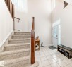 Bright entry foyer featuring a two-story ceiling, a white paneled door with decorative glass, and light-toned tile flooring - 8730 180A Avenue, Edmonton, AB 