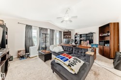 Spacious room featuring carpeting, multiple windows, a ceiling fan, and built-in shelving - 