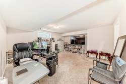 Carpeted room featuring a built-in entertainment center, recessed lighting, and a large window with blinds - 