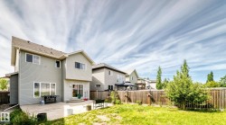 Expansive fenced backyard featuring a concrete patio, a sliding glass door, and green lawn - 