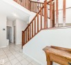 Foyer featuring a grand staircase with wood railings, a tiled floor, and a recessed ceiling light - 8730 180A Avenue, Edmonton, AB 