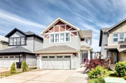 Two-story residence featuring light-toned horizontal siding with contrasting reddish-brown gables and trim - 