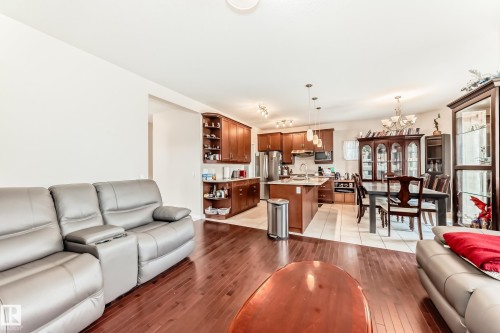 Open-concept living space with dark wood-finish flooring extending into the kitchen - 8730 180A Avenue, Edmonton, AB 