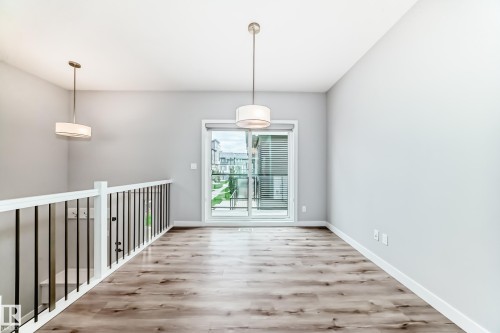 Spacious room featuring wood-finish flooring, light grey wall paint, and white baseboards - 26 1729 Keene Crescent, Edmonton, AB 