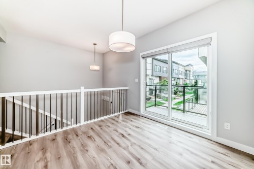 Open-concept space featuring wood-finish flooring and a contemporary pendant light fixture - 26 1729 Keene Crescent, Edmonton, AB 