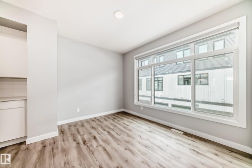 Spacious interior featuring large windows, wood-finish flooring, recessed lighting, and a built-in cabinet with a light countertop and tile backsplash - 26 1729 Keene Crescent, Edmonton, AB 
