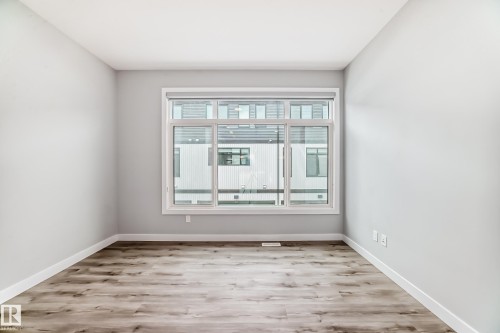 Spacious room featuring light gray walls, wood-finish flooring, and white baseboards - 26 1729 Keene Crescent, Edmonton, AB 