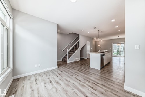Open-concept living area featuring wood-finish flooring, recessed lighting, and a kitchen island with pendant lighting - 26 1729 Keene Crescent, Edmonton, AB 