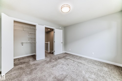 Carpeted room with a flush-mount ceiling light fixture, neutral wall paint, and a double-door closet with wire shelving - 26 1729 Keene Crescent, Edmonton, AB 