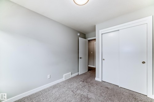 Spacious room featuring neutral carpeting, light gray wall paint, and white trim - 26 1729 Keene Crescent, Edmonton, AB 