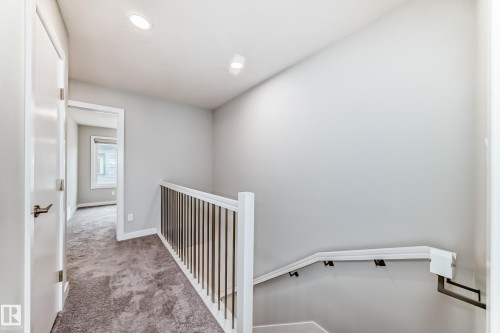 Upper-level landing featuring recessed lighting, a neutral gray carpet, white painted walls, and contemporary staircase balusters - 26 1729 Keene Crescent, Edmonton, AB 