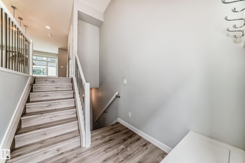 Staircase featuring wood-finish treads and risers, white balustrade, and dark metal spindles - 26 1729 Keene Crescent, Edmonton, AB 