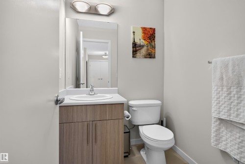 Contemporary bathroom featuring a wood-finish vanity with a white countertop and integrated sink, chrome faucet, and overhead bar lighting fixture - 4612 Westcliff Point(E), Edmonton, AB 