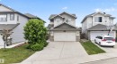 Front exterior featuring light gray siding, stone accents, a two-car garage, concrete driveway, and mature landscaping - 4612 Westcliff Point(E), Edmonton, AB 