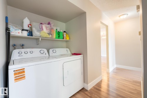 Dedicated laundry area featuring a white top-load washer and dryer set, an overhead storage shelf, and light-toned walls - 8 2703 79 Street, Edmonton, AB 