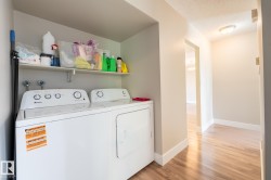 Dedicated laundry area featuring a white top-load washer and dryer set, an overhead storage shelf, and light-toned walls - 
