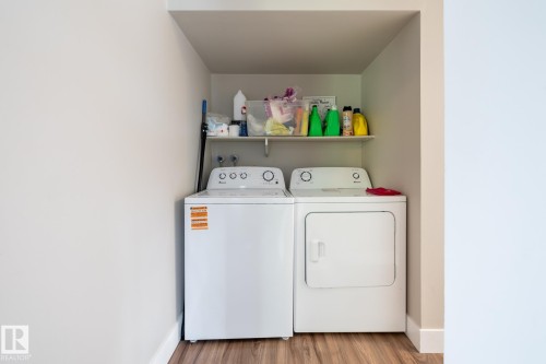 Dedicated laundry area featuring a white washing machine, white dryer, and a wall-mounted storage shelf - 8 2703 79 Street, Edmonton, AB 