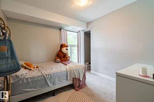 Carpeted room featuring a window with white drapes, light-toned walls, and a built-in overhead light fixture - 8 2703 79 Street, Edmonton, AB 