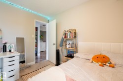 Neutral-toned bedroom featuring wall-to-wall carpeting and a spacious doorway opening to a utility area with shelving and a washer - 