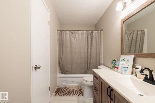 Bathroom with wood-finish vanity, white countertop, and dark-finish faucet - 8 2703 79 Street, Edmonton, AB 