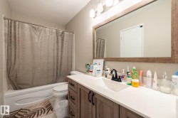 Bathroom featuring a wood-finish vanity with ample storage, a white countertop, and a rectangular undermount sink with a matte black faucet - 